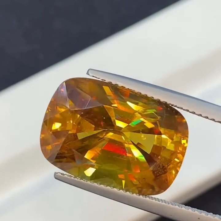 18.32 ct golden yellow sphene, cushion modified step cut, held in tweezers
