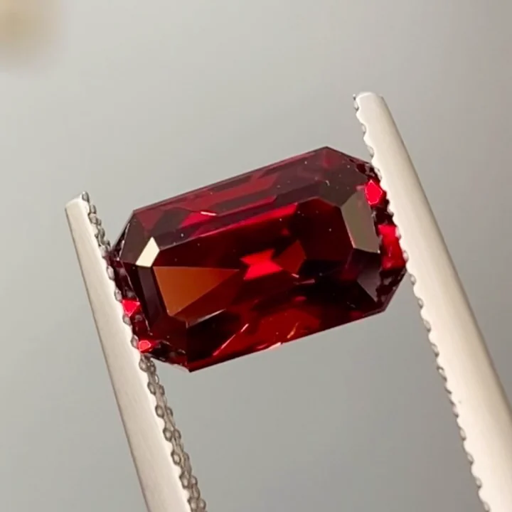 2.66 ct vivid red spinel, emerald cut, held in tweezers