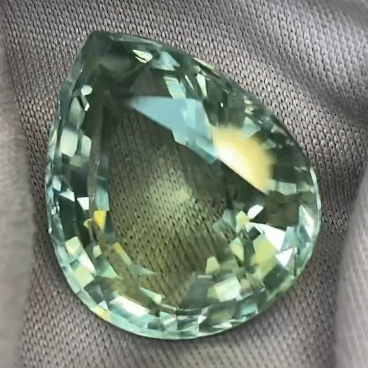16.78 ct seafoam green tourmaline, pear modified step cut, on grey cloth