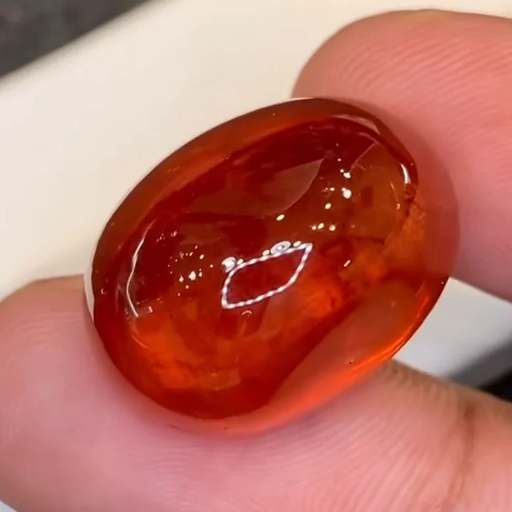 43.98 ct mandarin spessartite garnet cabochon held in the hand