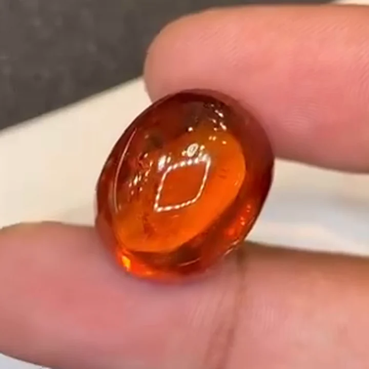 31.15 ct mandarin spessartite garnet drop cabochon held in the hand
