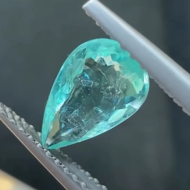 1.01 ct neon blue Paraiba tourmaline, pear shape, held in tweezers