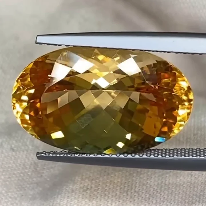 18.31 ct golden yellow imperial topaz, oval Portuguese cut, in tweezers