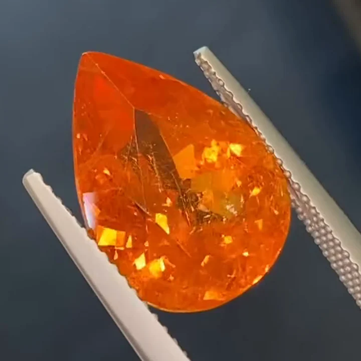 11.13 ct Fanta orange spessartite garnet, pear shape, in tweezers