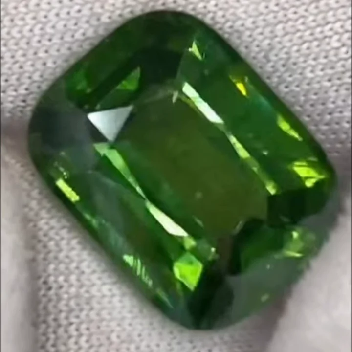 9.45 ct natural green zircon, cushion step cut, on cloth