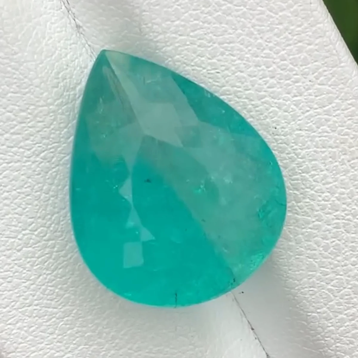 15.69 ct neon blue Paraiba tourmaline pear on a white tray