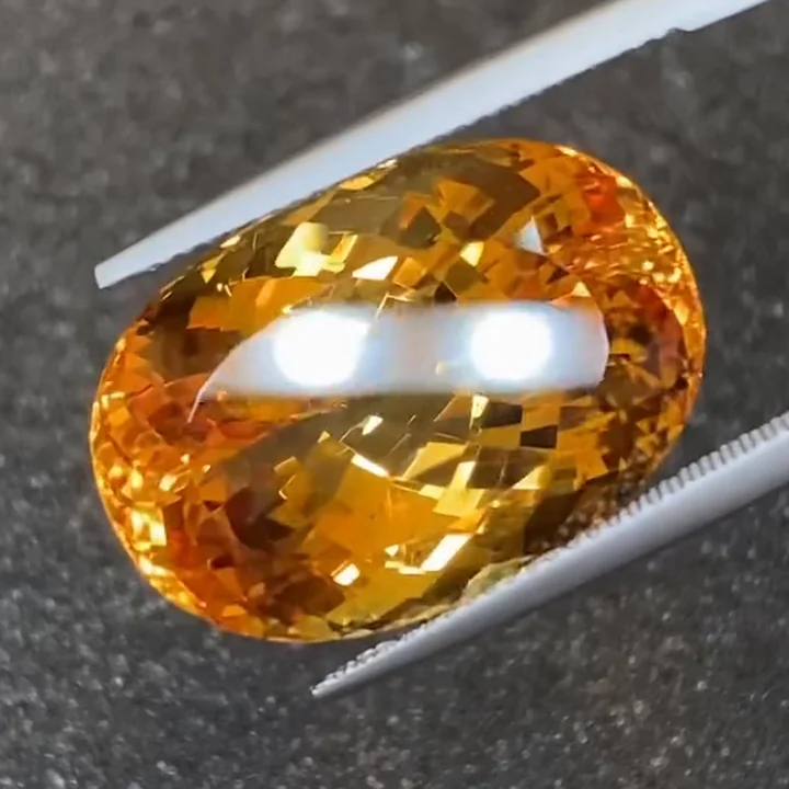 34.37 ct imperial topaz, oval, in tweezers