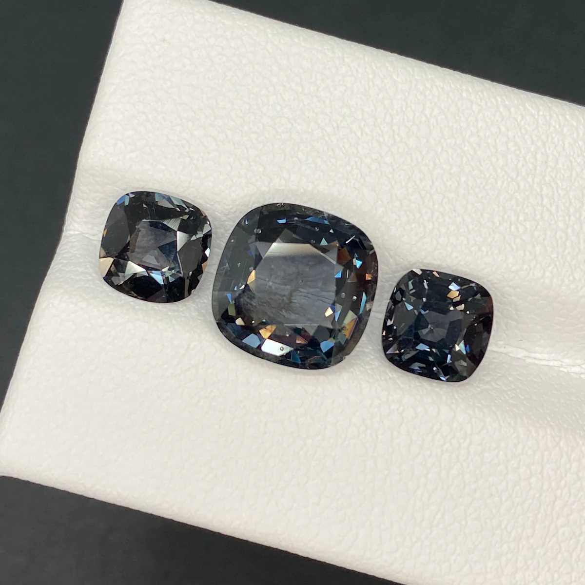 Metallic grey spinel trilogy, a 5.00 ct centre stone and a 3.50 ct pair, on a white tray