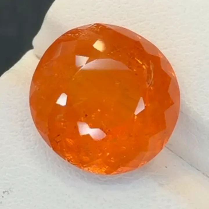 13.73 ct Fanta orange spessartite garnet, near round modified brilliant, on a white tray