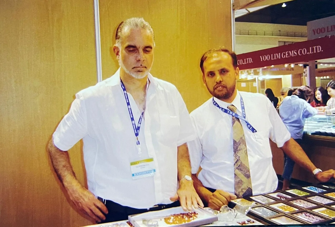 Mohamed Sirajudeen at a gem trade fair booth, with trays of stones on the table