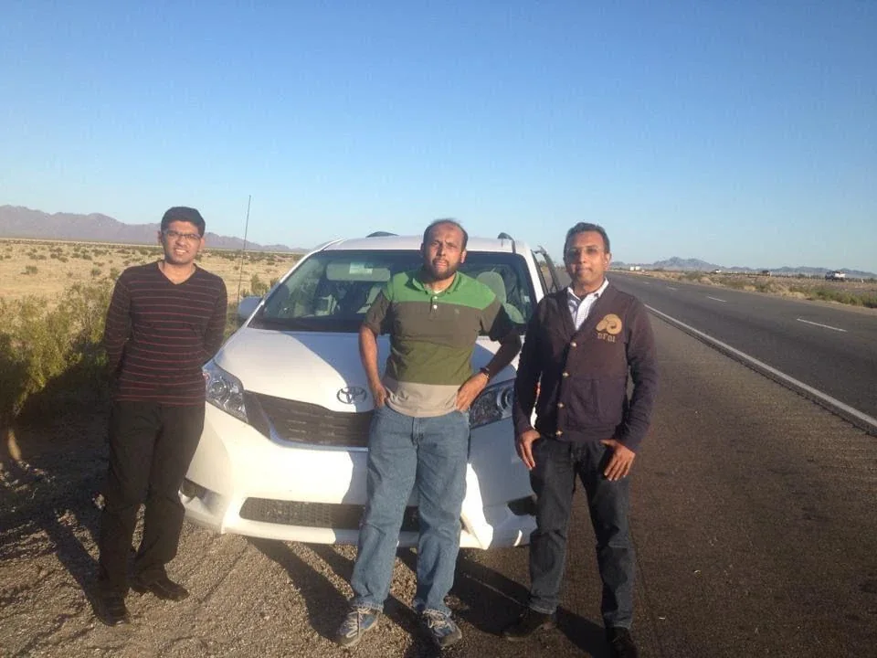 Mohamed Sirajudeen with two other men in front of a white van on a desert highway